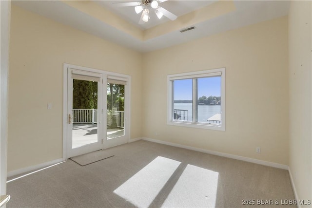 5482 Stoneledge Cir, Osage Beach, MO 65065 - carpeted empty room with ceiling fan, a water view, baseboards, and a tray ceiling