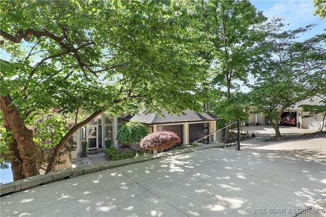 5482 Stoneledge Cir, Osage Beach, MO 65065 - view of property hidden behind natural elements with a garage and stucco siding