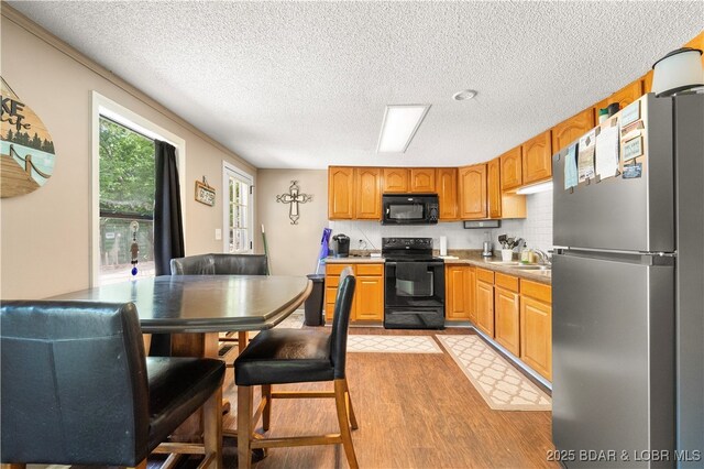 66 Old Shawnee Bend Rd, Sunrise Beach, MO 65079 - kitchen with black appliances, light wood-style floors, a textured ceiling, light countertops, and brown cabinets