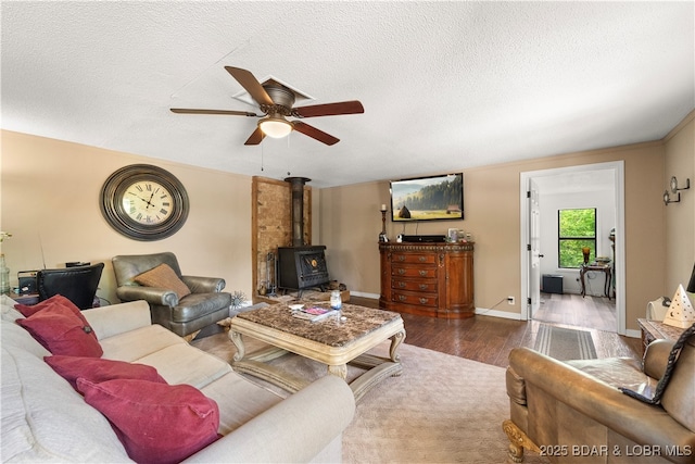66 Old Shawnee Bend Rd, Sunrise Beach, MO 65079 - living room with a wood stove, wood finished floors, ceiling fan, a textured ceiling, and baseboards