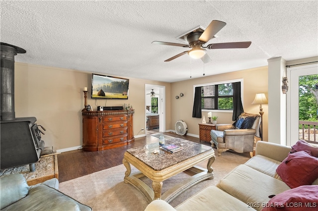 66 Old Shawnee Bend Rd, Sunrise Beach, MO 65079 - living room featuring a wood stove, ceiling fan, a textured ceiling, wood finished floors, and baseboards
