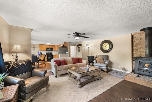 66 Old Shawnee Bend Rd, Sunrise Beach, MO 65079 - living room featuring a wood stove, light wood finished floors, ceiling fan, a textured ceiling, and baseboards