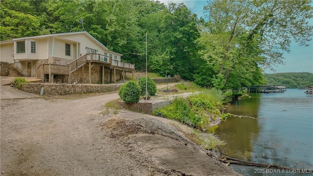 26587 Lake Front Ln, Rocky Mount, MO 65072 - view of property exterior with stairway, a forest view, a deck with water view, and driveway