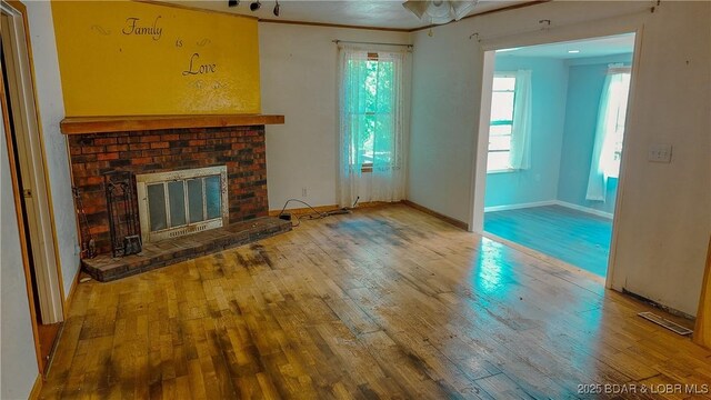 26587 Lake Front Ln, Rocky Mount, MO 65072 - unfurnished living room featuring wood-type flooring, plenty of natural light, and a brick fireplace