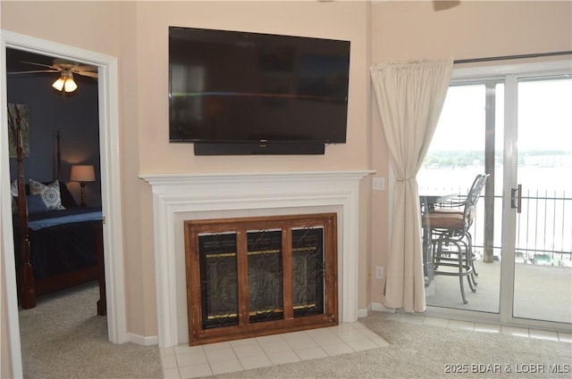 detailed view of a glass covered fireplace, a ceiling fan, carpet flooring, and baseboards