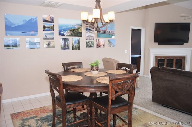 tiled dining space with a chandelier and a fireplace