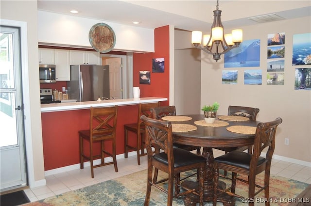 dining space with a chandelier, light tile patterned floors, and baseboards