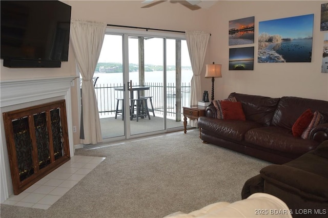 carpeted living room featuring a water view and a ceiling fan