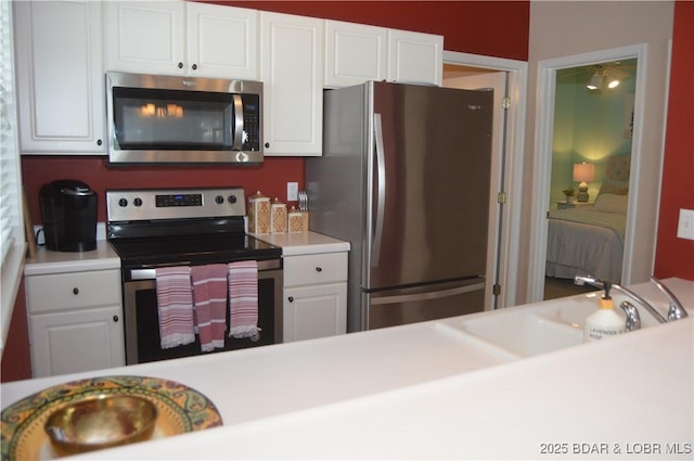 kitchen with stainless steel appliances, white cabinetry, a sink, and light countertops