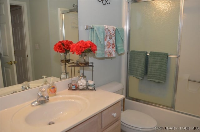 bathroom featuring toilet, vanity, and combined bath / shower with glass door