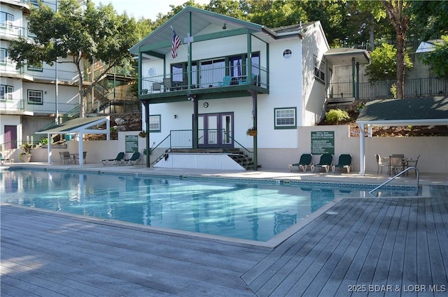 community pool with fence, french doors, and a patio area