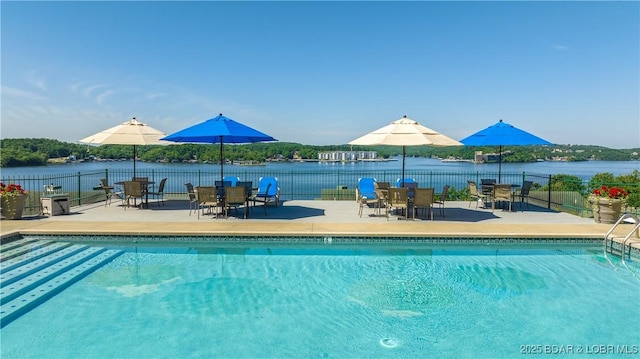 view of swimming pool featuring fence, outdoor dining space, a water view, and a patio area