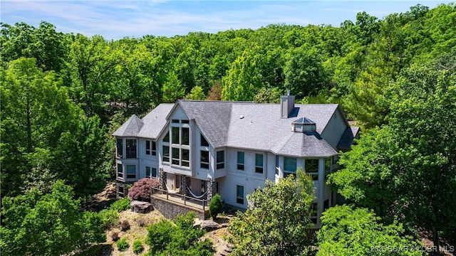 126 W Cross Fox Trl, Camdenton, MO 65020 - back of property featuring stucco siding, a chimney, a wooded view, and a shingled roof