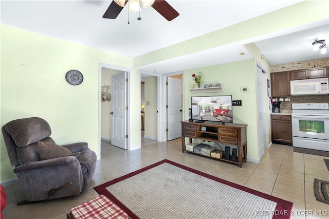 living area with light tile patterned floors, ceiling fan, and baseboards