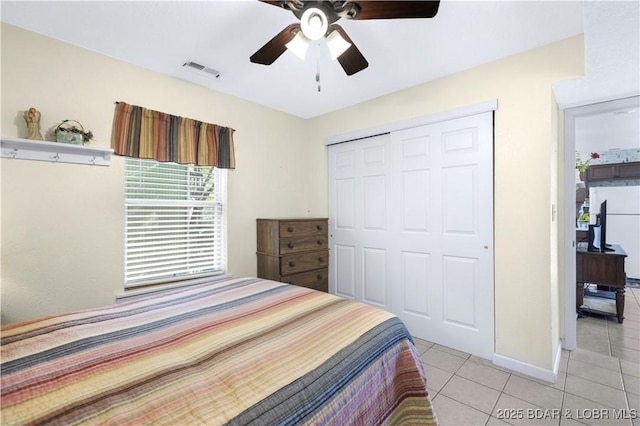 bedroom featuring light tile patterned floors, a closet, ceiling fan, and baseboards