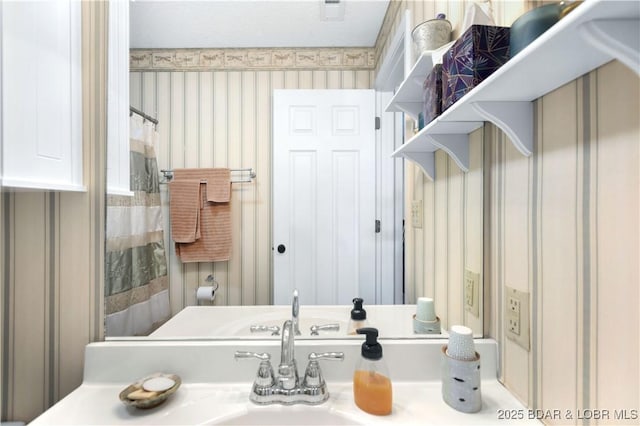 bathroom with wallpapered walls and vanity