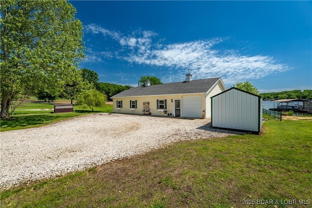 30566 Johnson Bay Dr, Gravois Mills, MO 65037 - back of property with driveway, an outbuilding, a lawn, and a storage unit