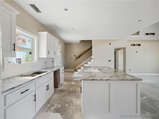 17 Eagles Pass, Climax Springs, MO 65324 - kitchen featuring unfinished concrete floors, a center island, white cabinets, and light stone counters