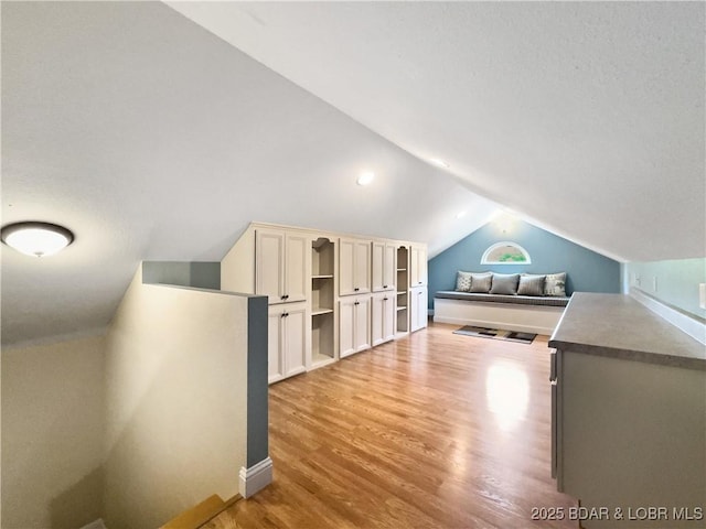 bonus room with lofted ceiling, light wood finished floors, and baseboards