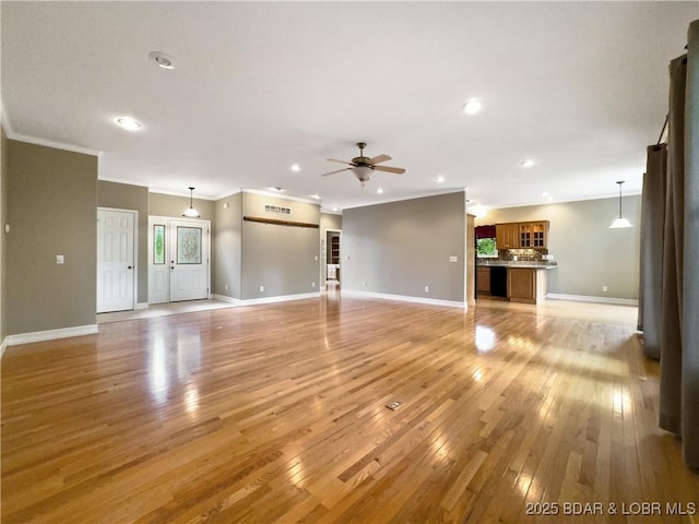 unfurnished living room featuring light wood finished floors, ornamental molding, ceiling fan, baseboards, and recessed lighting