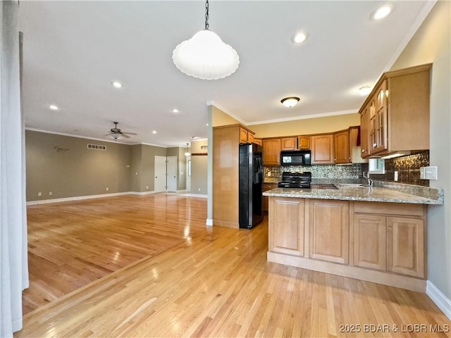 kitchen featuring black appliances, crown molding, tasteful backsplash, a peninsula, and baseboards