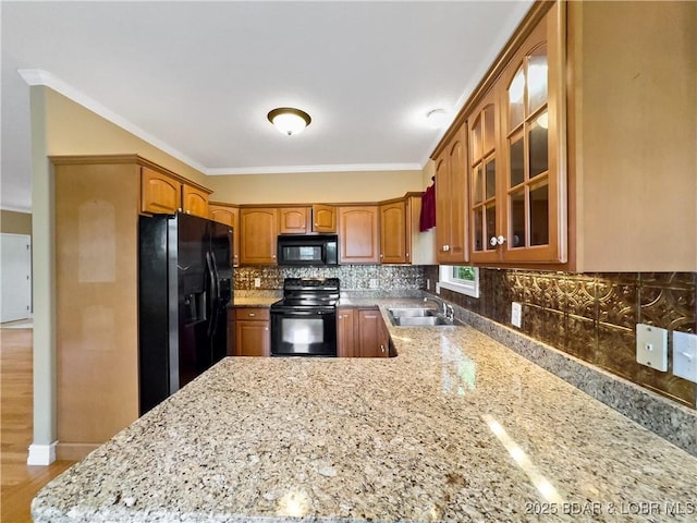 kitchen featuring black appliances, a sink, glass insert cabinets, decorative backsplash, and crown molding