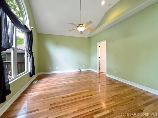 empty room featuring light wood finished floors, a ceiling fan, baseboards, and high vaulted ceiling