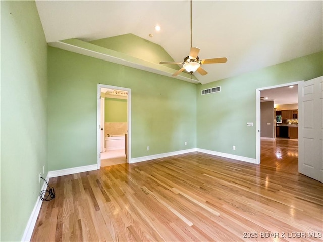 unfurnished bedroom featuring lofted ceiling, light wood-style floors, baseboards, connected bathroom, and a ceiling fan