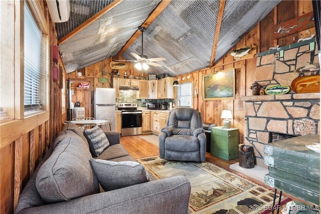 living area featuring wood walls, light wood-style flooring, vaulted ceiling, and a ceiling fan