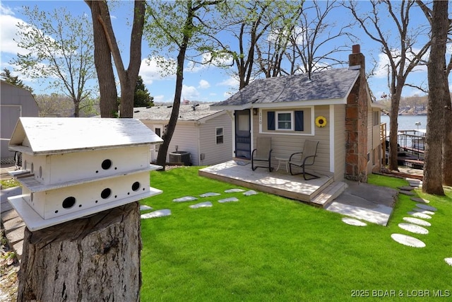 view of grassy yard featuring central AC and a deck with water view