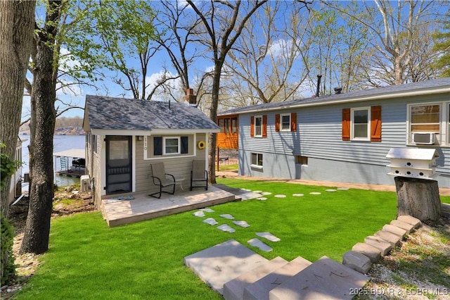 back of property featuring an outdoor structure, a lawn, and a deck with water view