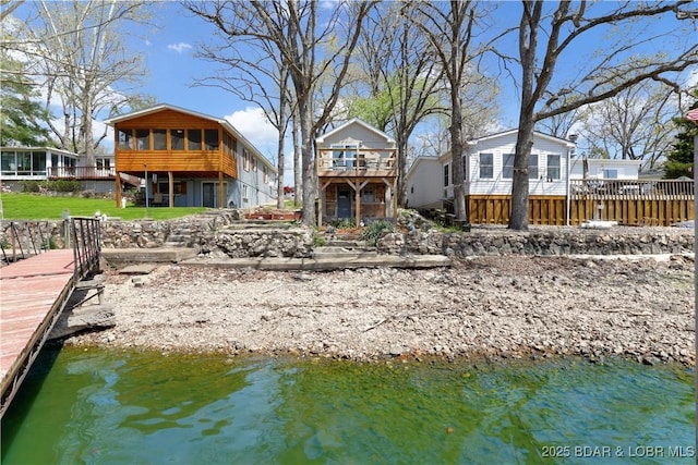 back of property with a sunroom and a water view