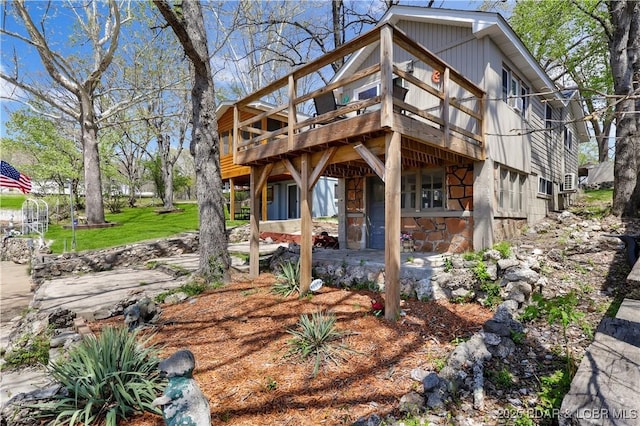 view of front of home with stone siding, a wooden deck, and a front lawn