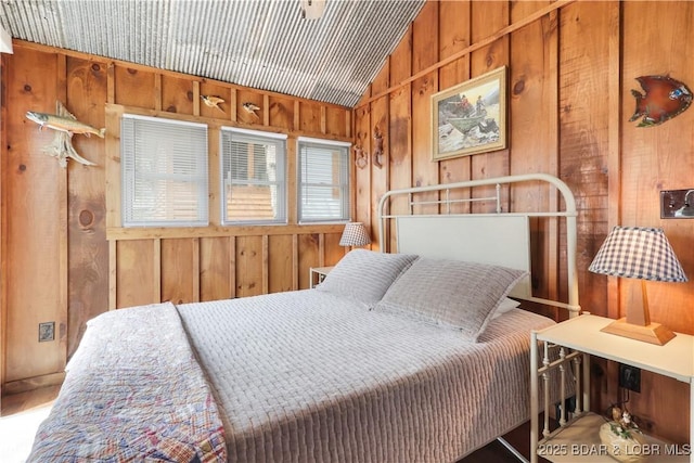 bedroom featuring wooden walls and lofted ceiling