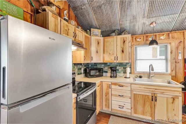 kitchen featuring stainless steel appliances, light brown cabinets, a sink, and light countertops
