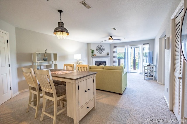 601 Park Place Dr Unit 2B, Kaiser, MO 65047 - kitchen with light carpet, a ceiling fan, a glass covered fireplace, decorative light fixtures, and a breakfast bar area