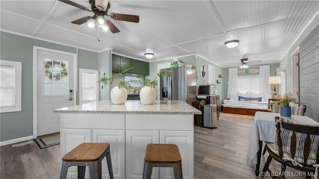 15219 Fleener Dr, Gravois Mills, MO 65037 - kitchen featuring a ceiling fan, wood finished floors, light stone counters, stainless steel refrigerator with ice dispenser, and baseboards