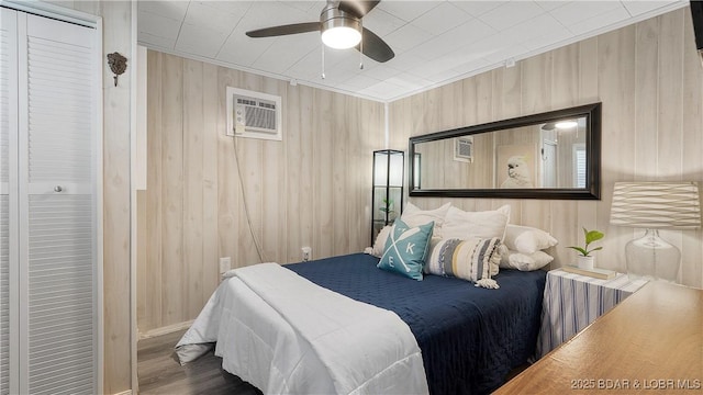 15219 Fleener Dr, Gravois Mills, MO 65037 - bedroom featuring wood finished floors, a wall mounted AC, a ceiling fan, wooden walls, and baseboards