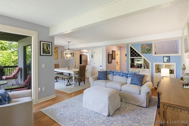 241 Shell Bay Cir Unit 1A, Linn Creek, MO 65052 - living room featuring wood finished floors, a textured ceiling, baseboards, and a chandelier