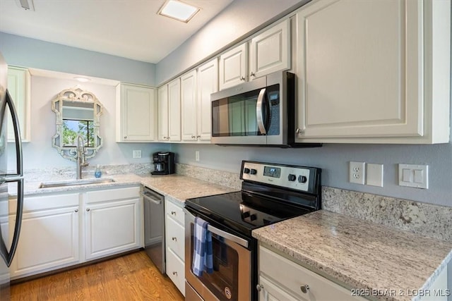 241 Shell Bay Cir Unit 1A, Linn Creek, MO 65052 - kitchen featuring appliances with stainless steel finishes, white cabinets, light wood-style flooring, and light stone counters
