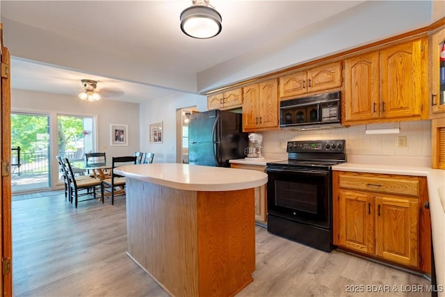 kitchen with black appliances, light wood-style floors, light countertops, and decorative backsplash