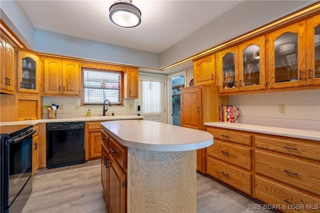 kitchen featuring black appliances, a sink, brown cabinetry, and backsplash