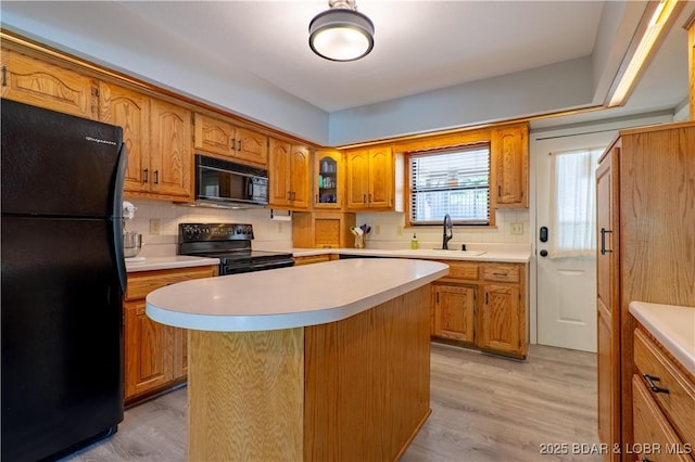 kitchen with black appliances, a sink, and light countertops