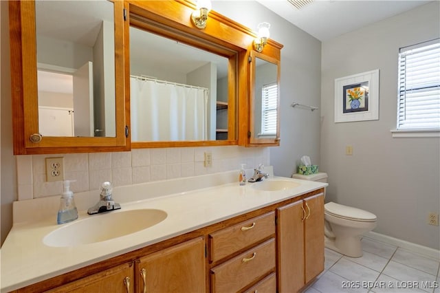 bathroom featuring tile patterned flooring, double vanity, toilet, and baseboards