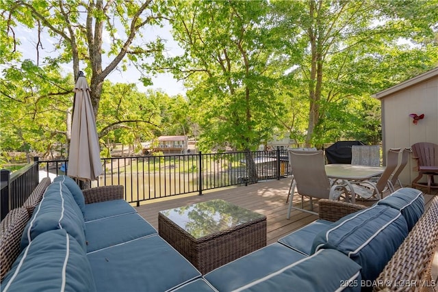 wooden deck with an outdoor hangout area, outdoor dining space, and view of scattered trees