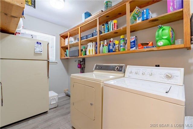 laundry room featuring washer and clothes dryer, light wood-type flooring, and baseboards