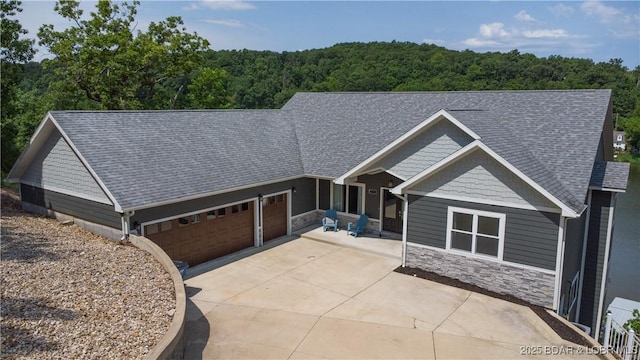 205 Wedge Wood Dr, Camdenton, MO 65020 - view of front of home with stone siding, a view of trees, an attached garage, concrete driveway, and roof with shingles
