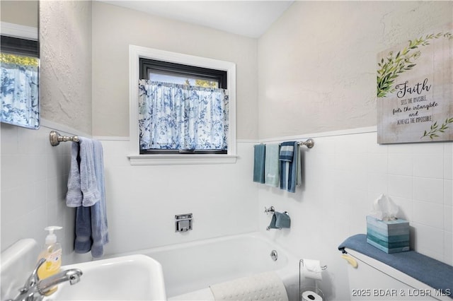 577 Mulberry Ln, Camdenton, MO 65020 - bathroom featuring a tub to relax in, a sink, toilet, tile walls, and wainscoting