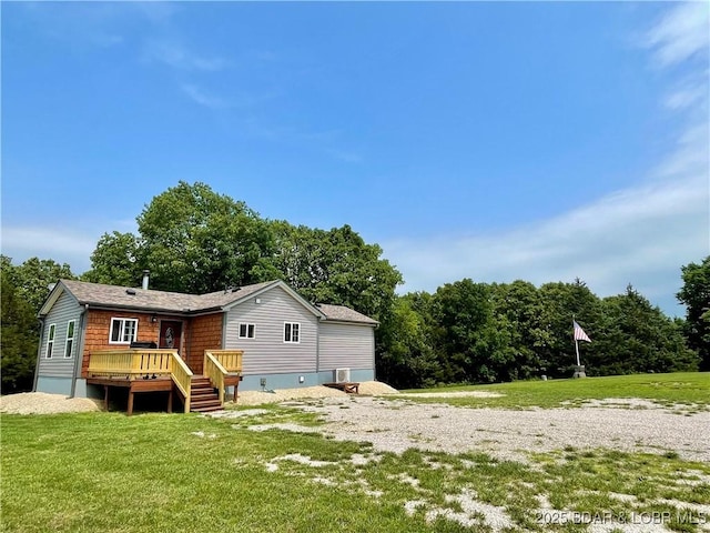 rear view of property with a wooden deck and a lawn