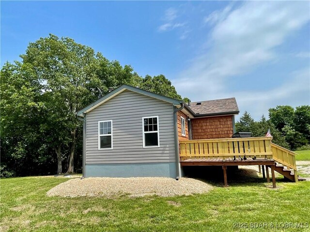 rear view of property with a deck, a lawn, and stairway